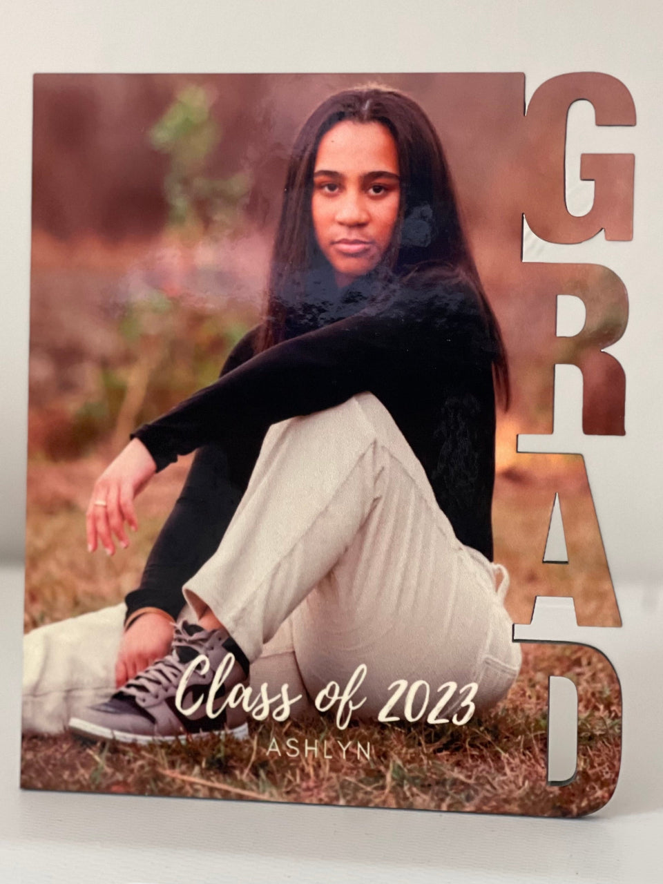 Graduation-themed photo album with a person sitting outdoors, featuring 'GRAD' and 'Class of 2023' text.