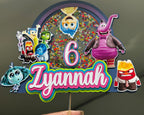 Colorful birthday cake topper with cartoon characters and '6 Zyannah' text on a gray background